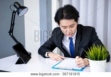 Asian Business Man Dringking Coffee Wearing Suit, Enjoying Watching Educational Webinar On Laptop Or