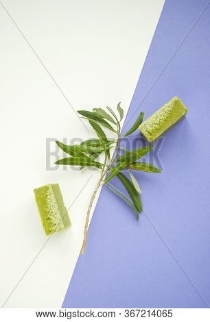 Flat Lay Of An Olive Branch, Handmade Olive Soap Bars On Purple And White Background.