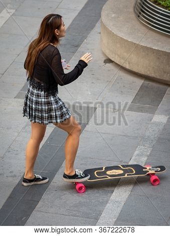 Beijing / China - August 21, 2016: Skater Girl Doing Tricks On A Skateboard In Modern Sanlitun Area 