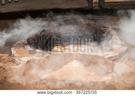 Smoke And Dust Fly As Food Is Being Prepared For A Traditional Maori Feast Or Hangi, By Steaming Thr