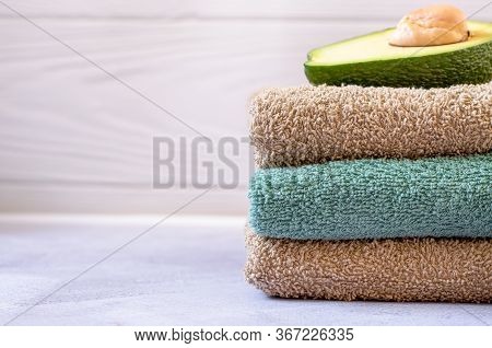 A Stack Of Three Bath Towels Of Brown And Turquoise Colors On A Light Background. On The Towel Lies 