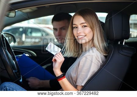 Joyful Girl Driving A Training Car With A Drivers License Card In Her Hands