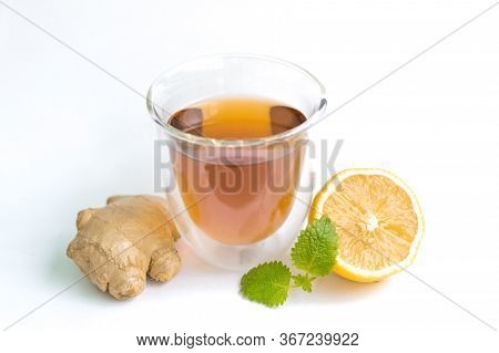 Transparent Glass With Tea And Fresh Ginger Root With Lemon And Mint Or Melissa Leaves On A White Is