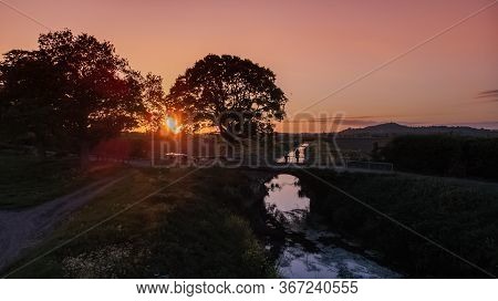 A Sunset Over A Riverbank In The Countryside Looking Out To Glastonbury Tor.