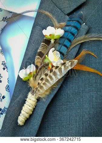 A Unique Feather Boutonierre On The Lapel Of The Groom At An Outdoor Wedding