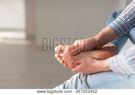 Man Hands Giving Foot Massage To Yourself To Relieve Pain After A Long Walk, Due To Uncomfortable Sh