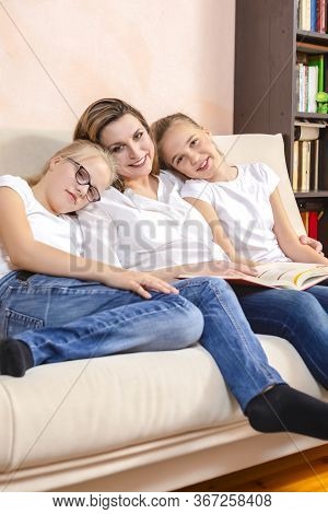 Home Staying Time. Portrait Of Young Caucasian Mother Reading A Book Together With Her Twin Daughter