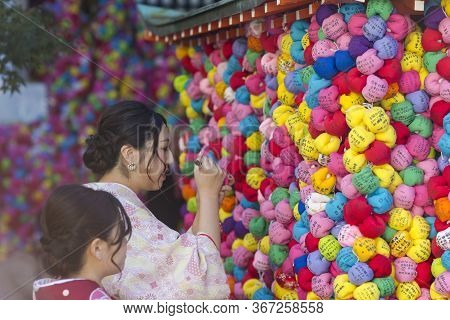 Kyoto, Japan - November, 8, 2019: Japanese Geisha Signing Colorful Temple Charm Formed As Colorful S