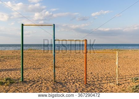Large Multi-colored Turnstiles Stand On The Beach With Clean Blue Sky.