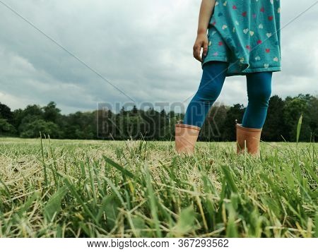 Closeup Of Girl Legs Feet In Rain Boots Walking On Meadow. Freedom, Innocence And Adolescense Concep