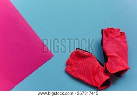 Flat Lay Pink Sports Weight Training Gloves For A Bicycle Or Gym Lie On A Blue And Pink Background. 
