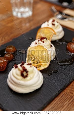 Meringue dessert with orange chips and sweet leechee jam on restaurant table