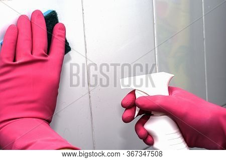 Bman In Rubber Household Gloves With A Sponge And Spray Washes A White Tiled Wall