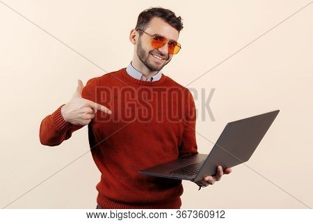 Stylish Bearded Young Man In Casual Outfit Pointing Finger On Notebook Or Computer Over Beige Backgr