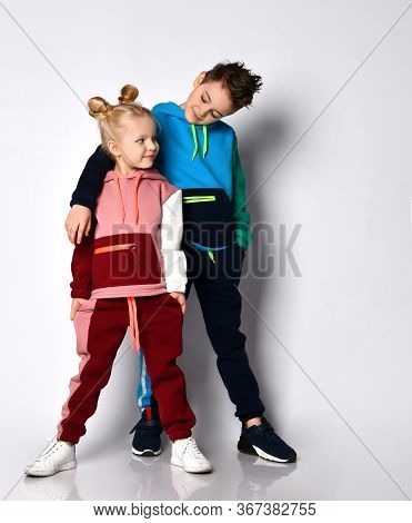 Smiling Elder Brother Putting Hand On Shoulder Of Younger Sister. Both Kids In Stylish Track Suits W