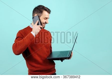 Handsome Bearded Young Man In Casual Outfit With Notebook Or Computer Talk On Smartphone Over Cyan B