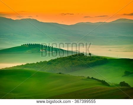 Amazing colorful sunset in Tuscany. Picturesque agrotourism and typical curved road with cypress, Crete Senesi rural landscape in Tuscany, Italy, Europe