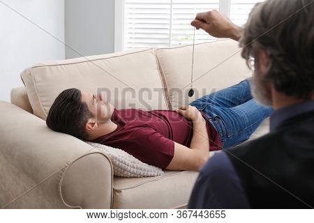 Psychotherapist Using Pendulum During Hypnotherapy   Session In Office