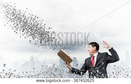 Expressive Businessman Holding Open Book. Emotional Man In Suit Standing On Downtown Background With