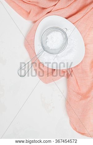 Powdered Confectioners Sugar In Sieve. Closeup Over Pastel Background.