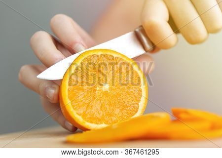 Close Up Hands Cutting A Ripe Juicy Orange With A Knife. Healthy Fruit Food Preparation Concept
