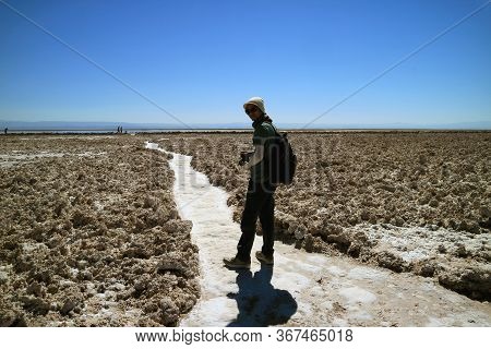 Traveler Walking On The Trail Of Salar De Atacama, Extensive Chilean Salt Flat At The Altitude Of 2,