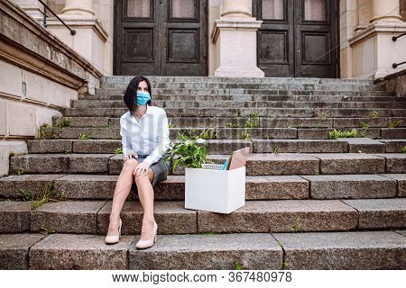 Young Business Woman In Office Siut Sitting On Old Stairs With A Box Of Her Office Supplies And Sign