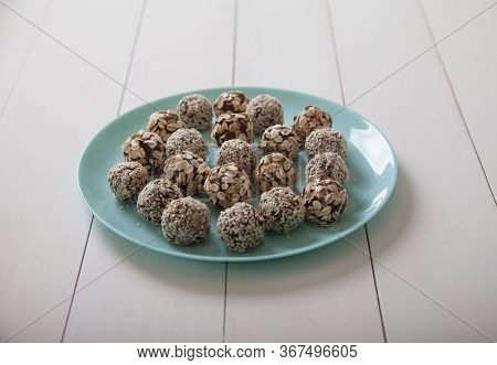 Energy Balls Of Dried Fruits And Nuts Sprinkled With Sesame And Granola Lie On A Blue Porcelain Plat