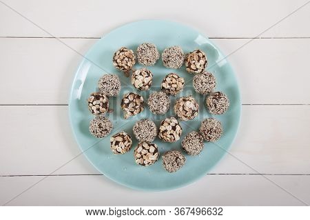 Energy Balls Of Dried Fruits And Nuts Sprinkled With Sesame And Granola Lie On A Blue Porcelain Plat