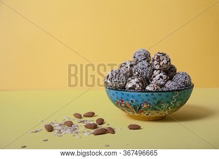 Energy Balls Of Dried Fruits And Nuts Sprinkled With Sesame And Granola Lie On A Blue Porcelain Plat