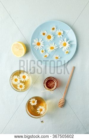 Chamomile Flowers And Chamomile Tea. Chamomile Tea In Glass Teacup With Flowers, Honey And Lemon, To