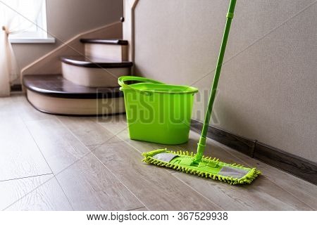Green Mop Standing Near White Wall. Cleaning Gear. Green Plastic Bucket. Householding.