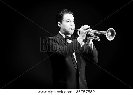 Retrato de um músico tocando a trombeta. Fundo preto.