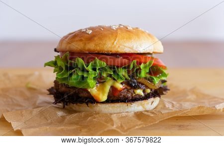 Homemade Cheesburger Lying On A Piece Of Gray Paper. Picture Taken In German