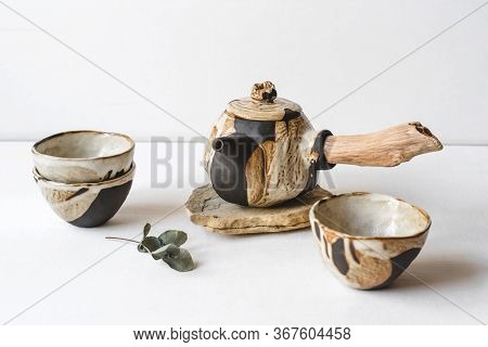 Handmade Ceramics In The Style Of Wabi Sabi. Brown Clay Teapot And Cups With An Abstract Pattern.