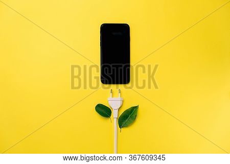Creative Top View Flat Lay Of Modern Smartphone With Plug Like A Plant With Copy Space On Yellow Bac