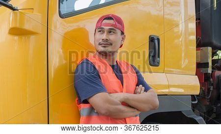 An Asian Man Was Smiling Happily Beside The Yellow Truck. He Has A Career As A Transport Driver. The