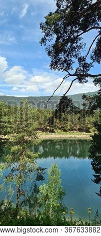 Engolasters Lake Side View With Trees Reflected Over The Water