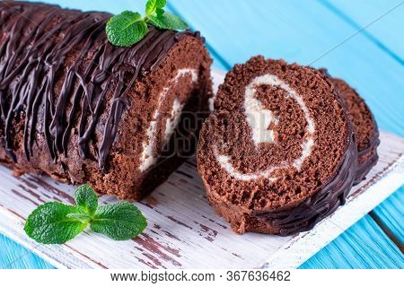 Cocolate Roll With White Fillings On A Blue Background. Desert Sweet Food