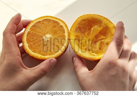 Half A Whole And Half Squeezed Orange In A Woman's Hands After Making Juice Using A Manual Juicer On