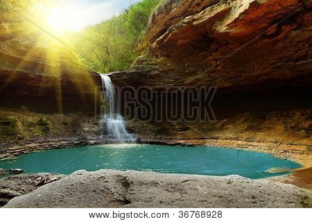 Cascada en las montañas iluminadas por el sol