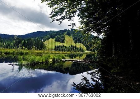 View Over Lispach Lake In La Bresse, France To Hills With Slope