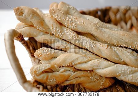 Italian Grissini Or Salted Breadsticks. Sesame Breadsticks In A Craft Paper On White Wooden Table. C