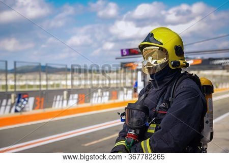 Firefighter With Yellow Helmet And Reflective Watching On Race Track In Broad Daylight