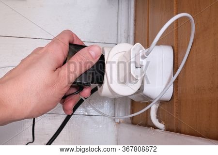 Overloaded Outlet With An Extension And Many Sockets Plugged In, A Hand Plugging A Socket Into The O