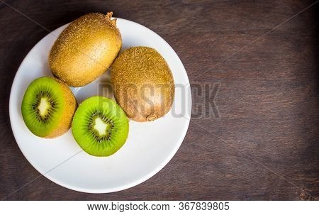 Kiwi On A White Plate With Dark Wood Background,copy Space