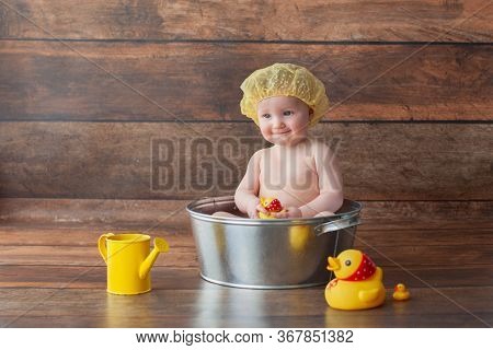 One Year Old Baby Takes A Bath. Bathed In A Basin With Rubber Ducks.