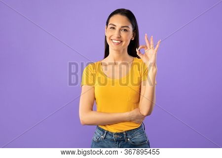 Im Fine. Smiling Brunette Woman Showing Ok Sign And Looking At Camera Isolated Over Pastel Purple Wa