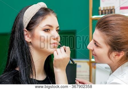 Makeup Artist Makes Outline With Lip Pencil On Lips Of Model In Beauty Salon.