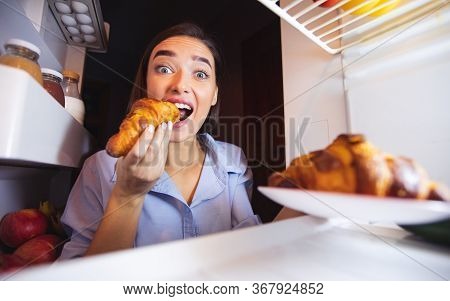 Cheat Meal. Young Girl Biting Croissants From Fridge, View From Inside